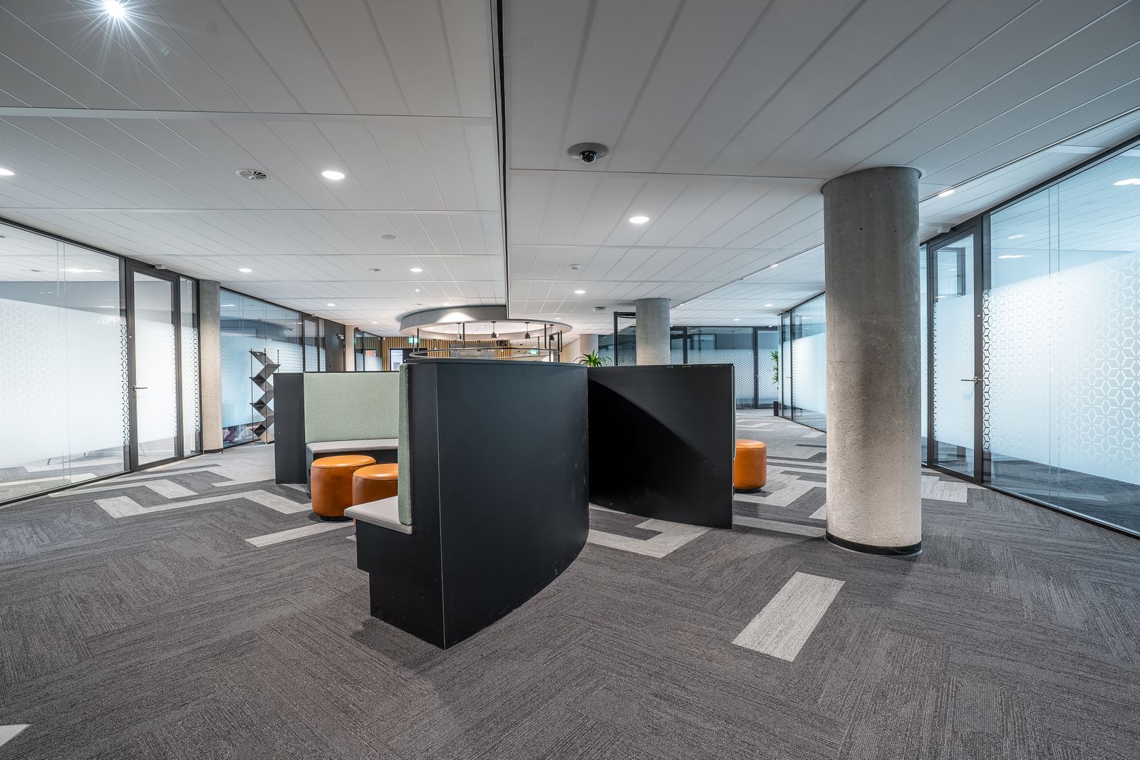 Modern office floor with glass partitions and lounge seating