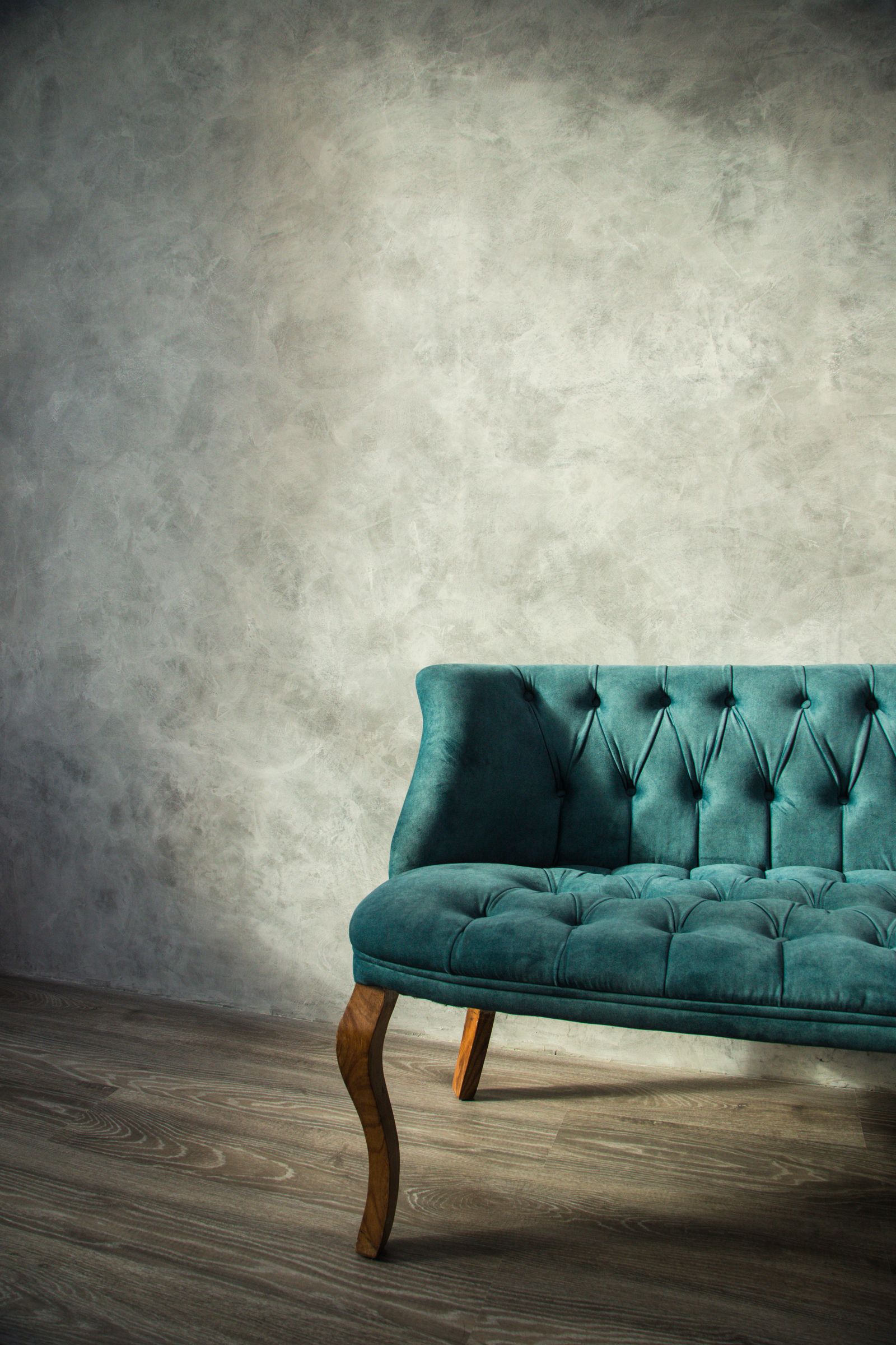 Sillón capitonado color verde azulado con patas de madera