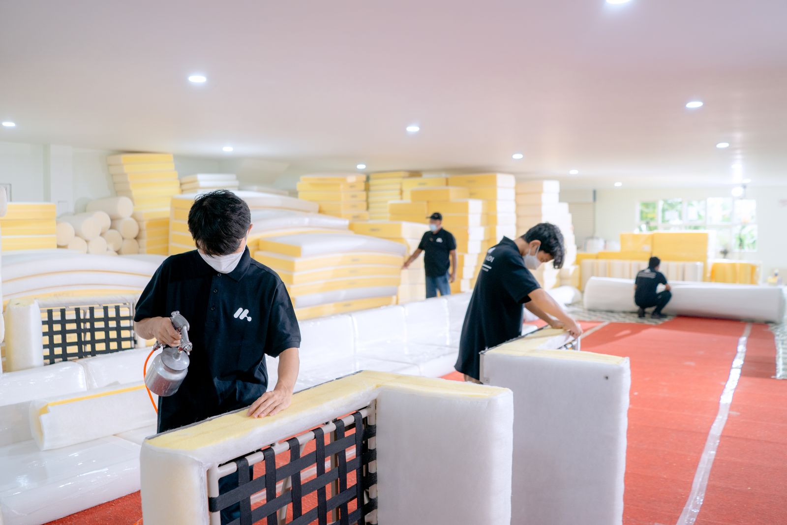 Operarios tapizando estructuras de sofá en un taller de muebles